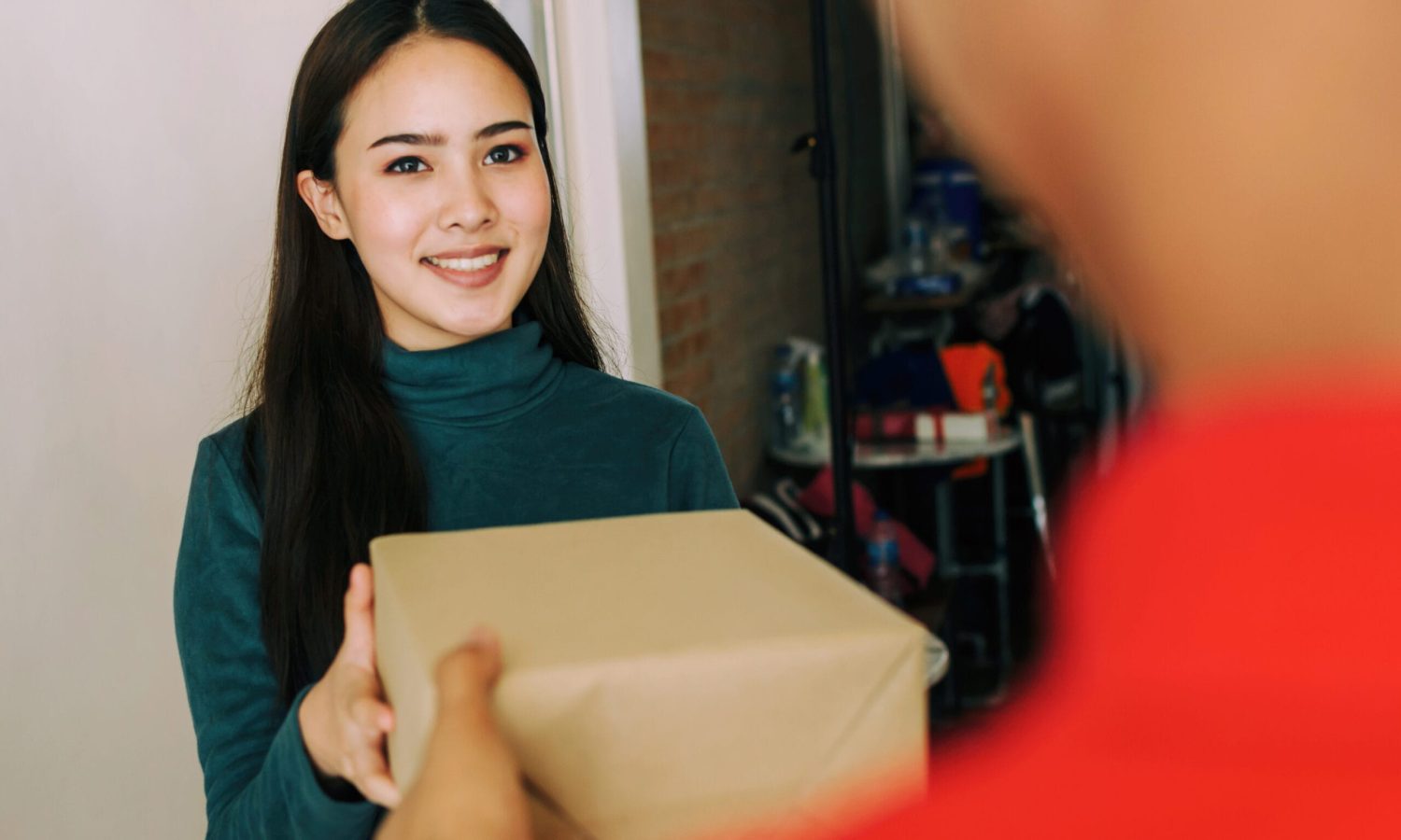 happy young asian woman customer smiling receive parcel post box from home delivery service man in red uniform at home, express home delivery service, logistics shipping and online shopping concept