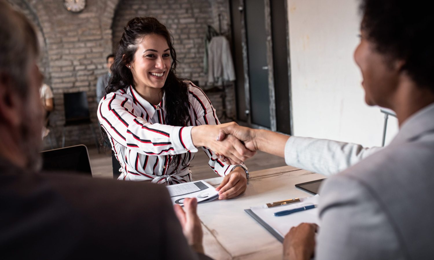 Young woman shakes hands with employer at job interview.