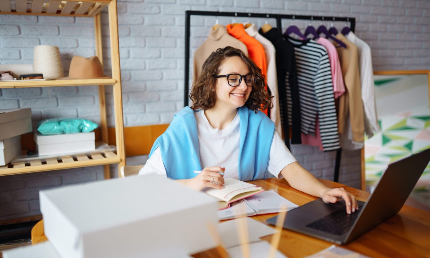 Young woman takes notes of orders from with laptop. Dropshipping business owner working in her office.  Startup business. Online sales.